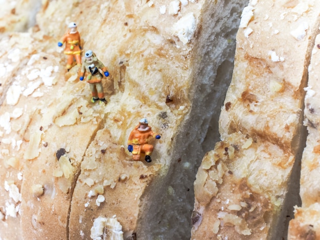 Personnages miniatures: Trois explorateurs escaladent une montagne de kilos de pain.