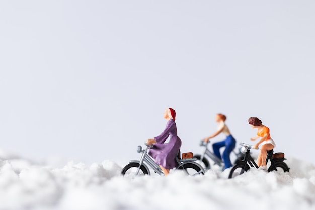 Personnages miniatures: voyageurs à vélo sur la neige