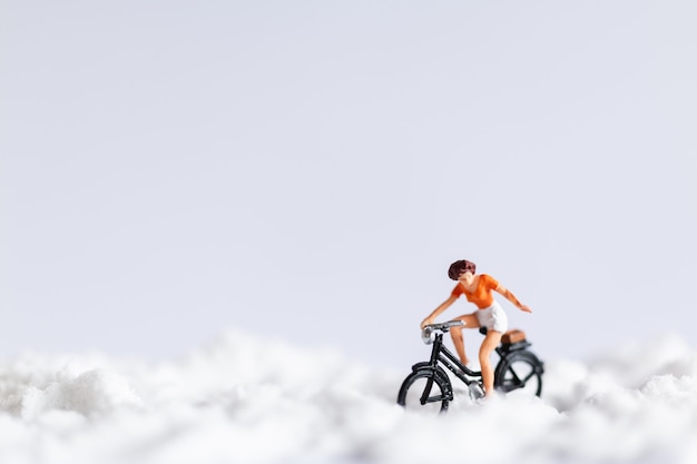 Personnages miniatures: voyageurs à vélo sur la neige