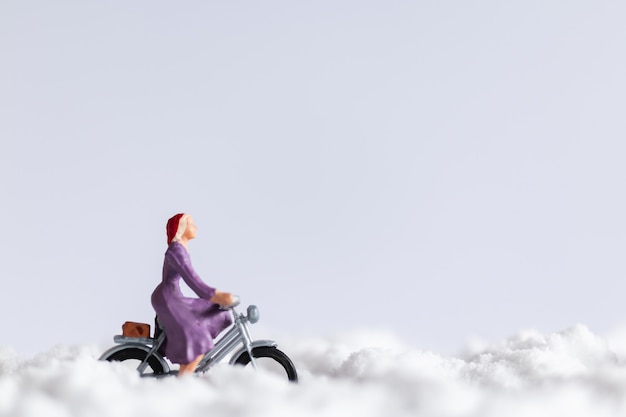 Personnages miniatures: voyageurs à vélo sur la neige