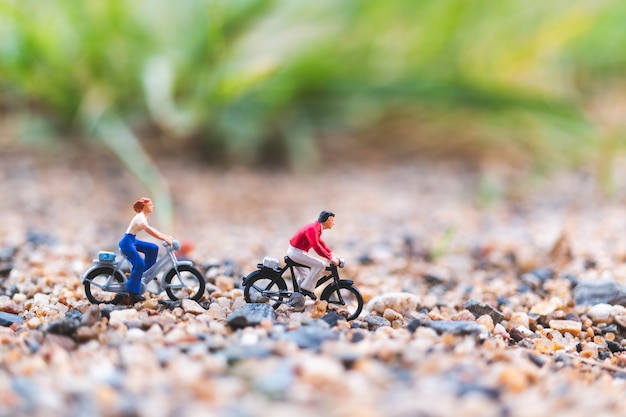 Personnages miniatures: voyageurs à vélo sur le sable