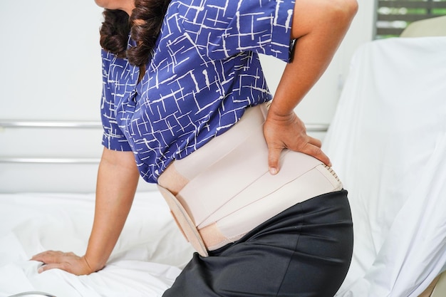Une personne âgée asiatique portant une ceinture de soutien élastique peut aider à réduire les maux de dos