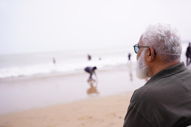 Photo une personne âgée assise devant l'océan et appréciant son moment de vie