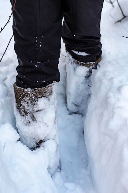 Une personne en bottes après de fortes chutes de neige essaie de se frayer un chemin dans une épaisse couche de neige