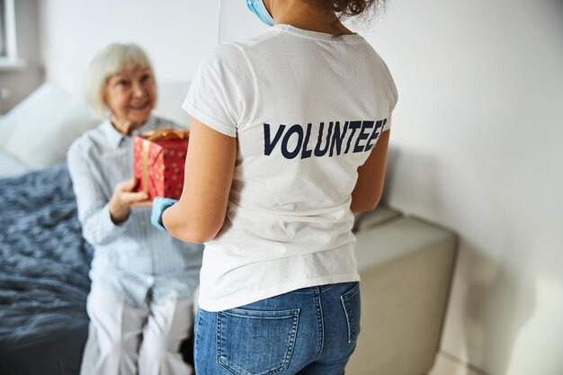 Personne en chemise de bénévole livrant une boîte cadeau