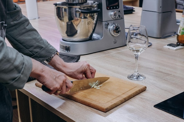 Une personne coupe un morceau de fromage sur une planche à découper avec un grand verre de vin à côté.