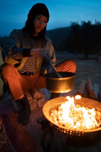 Personne cuisinant au feu de camp