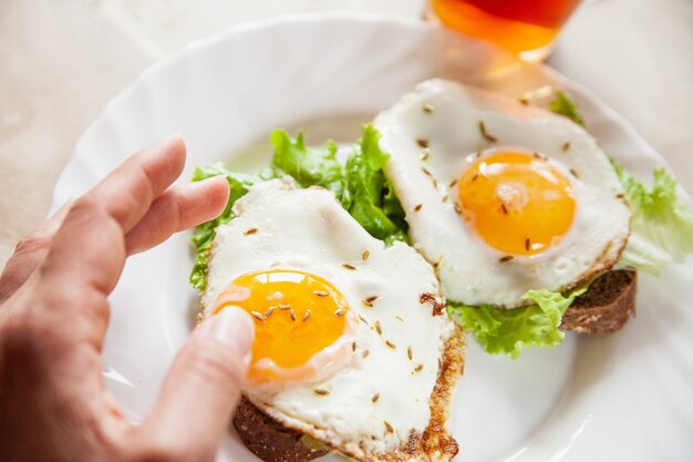 Personne de culture mangeant des toasts avec des oeufs au plat