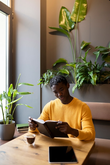 Photo personne dans un café lisant un livre