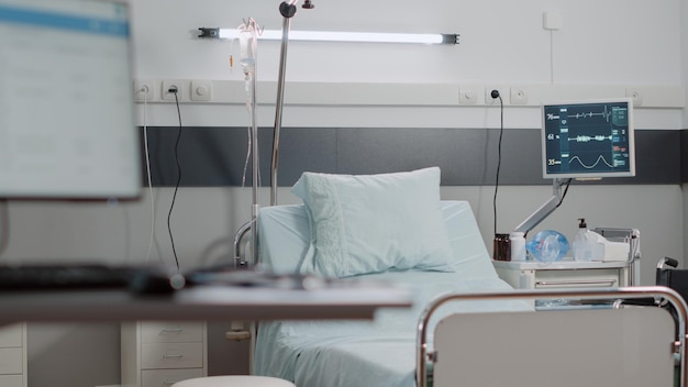 Personne dans le lit de la salle d'hôpital de l'établissement de soins intensifs. Salle d'urgence vide avec moniteur de fréquence cardiaque, sac d'égouttement IV, tube à oxygène et bouteille de pilules pour les soins de santé et la récupération