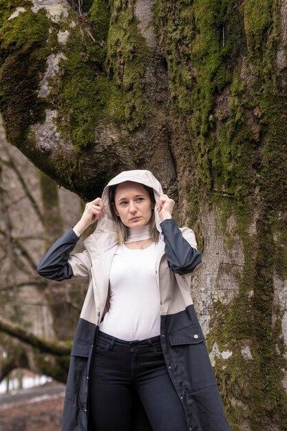 Photo personne dans une veste beige debout devant un arbre de mousse