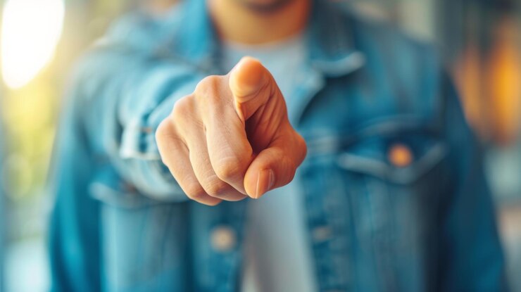 Photo une personne dans une veste en jean pointe directement vers la caméra avec l'accent sur le doigt pointant et le fond flou