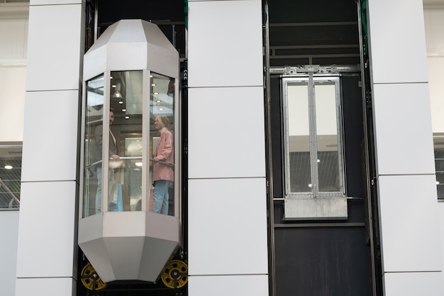 Une personne debout dans un ascenseur en mouvement à l'intérieur d'un grand centre commercial contemporain