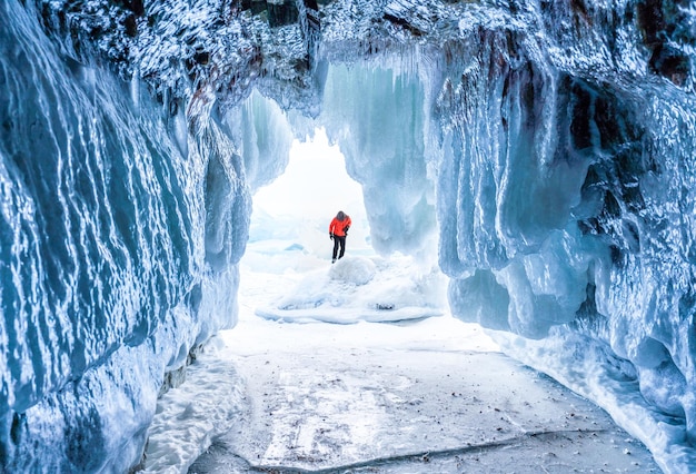 Personne debout sur la neige vue à travers l'entrée de la grotte