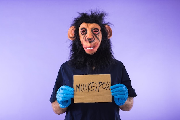 Personne déguisée avec un masque de singe portant une tenue d'infirmière médicale tenant une pancarte indiquant MONKEYPOX sur fond violet Épidémie de virus pandémique Nigeria et concept de variole