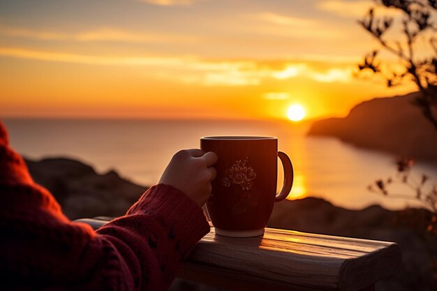 Photo une personne dégustant une tasse de café alors qu'elle est assise sur un balcon surplombant l'océan