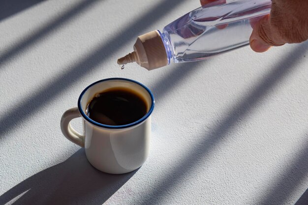 personne édulcorant le café avec de l'édulcorant liquide