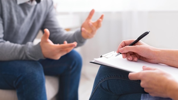 Une personne est assise dans un bureau de couleur neutre en train de discuter avec un autre individu