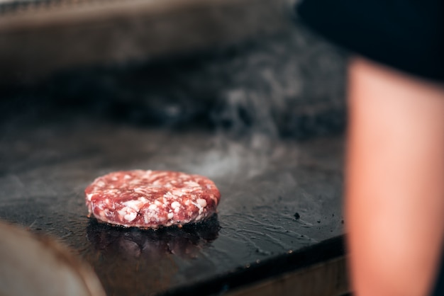 personne faisant cuire la galette de burger.