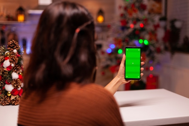 Personne festive tenant un smartphone avec écran vert