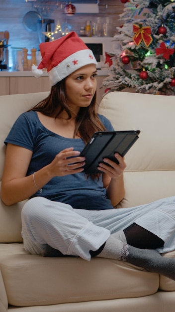 Personne festive travaillant sur tablette et regardant la télévision la veille de Noël