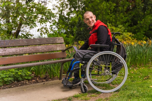 Une personne handicapée dans un parc public de la ville dans le portrait en fauteuil roulant à côté d'un banc de parc