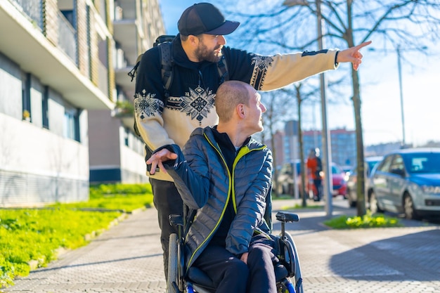 Une personne handicapée en fauteuil roulant avec un ami se promenant en s'amusant normalité pour les handicapés