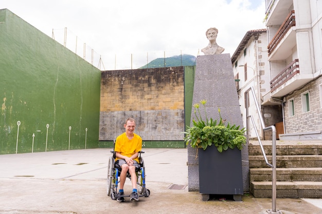 Une personne handicapée en fauteuil roulant à côté d'une sculpture sur la place de la ville