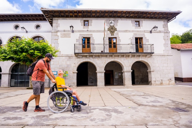 Une personne handicapée en fauteuil roulant marchant sur la place de la ville s'amusant avec un ami