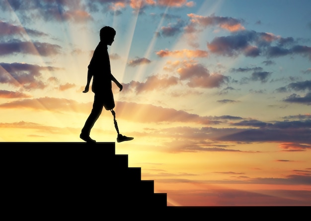 Une personne handicapée avec une jambe prothétique descend les escaliers au coucher du soleil