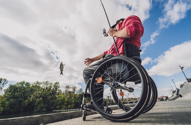 Personne handicapée physique en fauteuil roulant pêchant depuis un quai de pêche