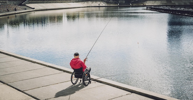 Personne handicapée physique qui utilise un fauteuil roulant pour pêcher depuis un quai de pêche