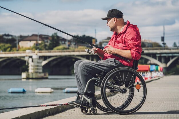 Personne handicapée physique qui utilise un fauteuil roulant pour pêcher depuis un quai de pêche
