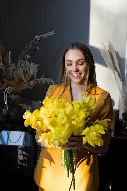 Photo une personne à l'intérieur tenant un bouquet de fleurs jaunes contre un mur 4659