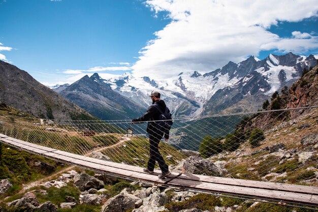 Une personne jeune homme marchant sur un pont suspendu en Suisse, randonnée avec un beau paysage voyageant