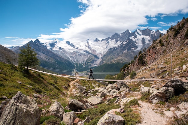 Une personne jeune homme marchant sur un pont suspendu en Suisse, randonnée avec un beau paysage