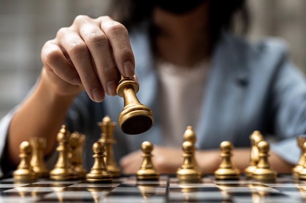 Personne jouant au jeu d'échecs, image de concept de femme d'affaires tenant des pièces d'échecs comme la concurrence commerciale et la gestion des risques, planifiant des stratégies commerciales pour vaincre les concurrents commerciaux.