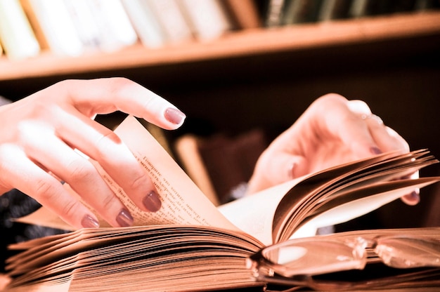 Une personne lisant un livre avec des lunettes sur la table.