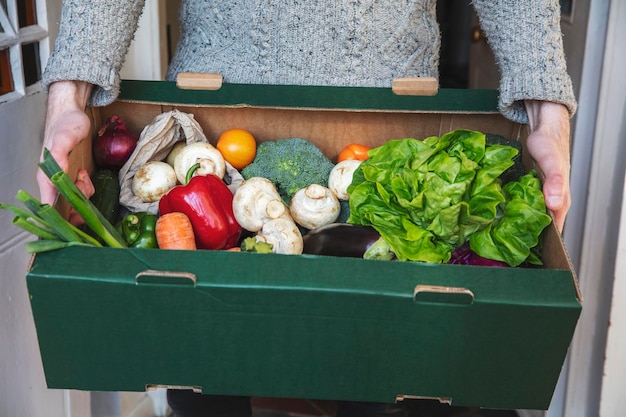 Une personne livrant une boîte de légumes frais faisant des achats d'aliments biologiques en ligne