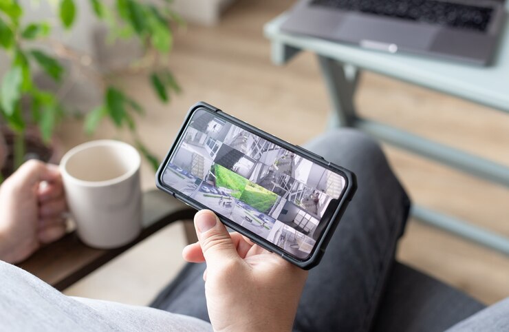 personne main tenant un smartphone avec plusieurs vues de caméra de surveillance des emplacements de bureau