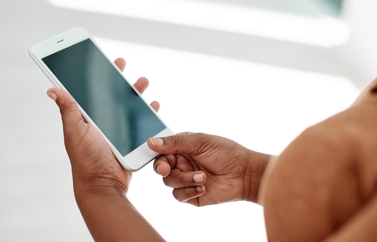 Photo personne mains et écran sur le lieu de travail avec smartphone pour réseau social site web mobile et contact numérique femme navigant sur téléphone portable lecture notification d'entreprise et recherche de médias sur maquette d'application