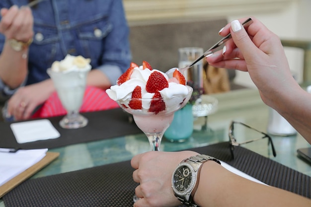 Une personne mangeant un dessert avec des fraises et de la crème fouettée