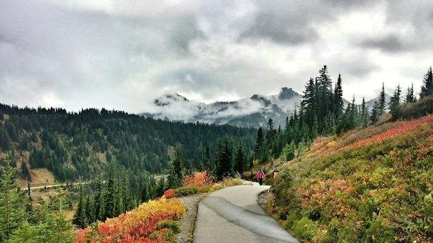 Une personne marchant sur le trottoir à travers les montagnes contre un ciel nuageux