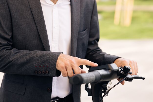 Une personne méconnaissable allume le scooter électrique L'homme active un scooter électrique une direction