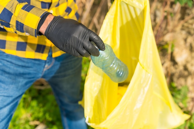 Personne méconnaissable ramassant du plastique et des ordures dans une forêt Recyclage du concept d'écologie