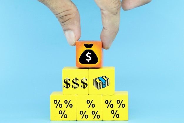 Une personne met un sac d'argent sur un cube qui indique un pourcentage.