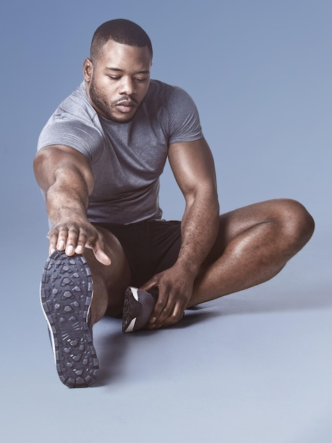 Photo personne n'aime les muscles raides. photo pleine longueur d'un beau jeune homme assis et s'étirant dans le studio.