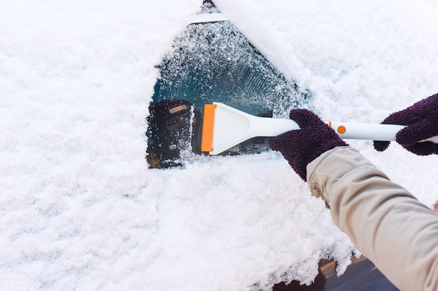 La personne nettoie la neige des fenêtres de voiture