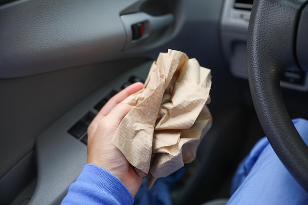 Une personne nettoie un sac en papier dans une voiture.