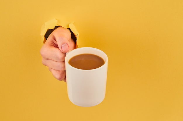 Personne non reconnaissable tenant une tasse de café sur fond orange